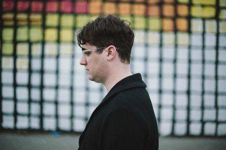 Joel Goodman in profile against a colorful grid background