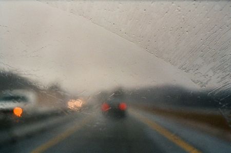 Car taillights through a blurry wet windshield during a rainstorm.