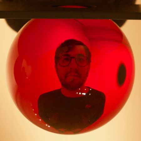 My head distorted as seen through a red glass sphere.