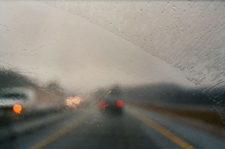 Car taillights through a blurry wet windshield during a rainstorm.